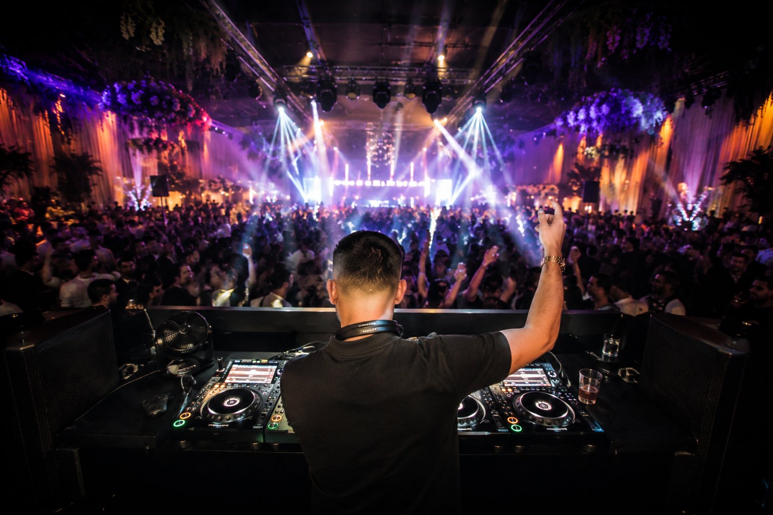DJ aux platines devant une foule sous les jeux de lumière